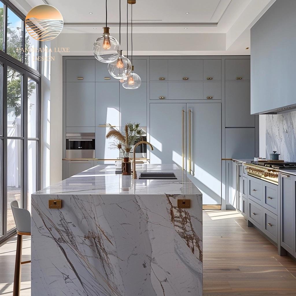 A modern kitchen with blue cabinetry and a marble island featuring a gold faucet and pendant lights.