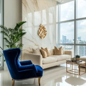 Bright luxury living room with marble feature wall, blue chair, and gold accents during the day.
