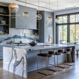 A kitchen with a marble island, gold light fixtures, and blue cabinets, with a scenic outdoor view.