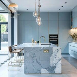 A sleek kitchen featuring a curved marble island, blue cabinetry, and golden light fixtures.