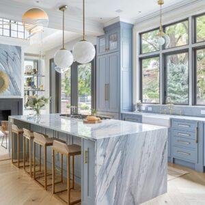A modern kitchen with marble countertops, a blue island, and round gold pendant lights.