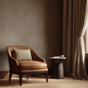 Leather lounge chair beside a sculptural side table and draped curtains in warm neutral tones near a window.